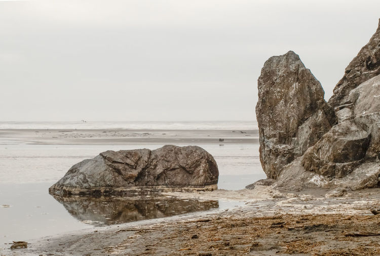 Rock formation on beach against sky