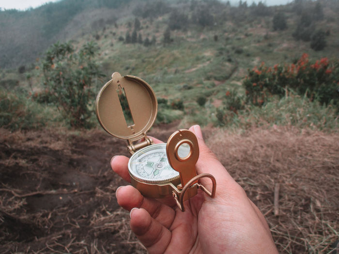 Cropped hand of woman holding navigational compass