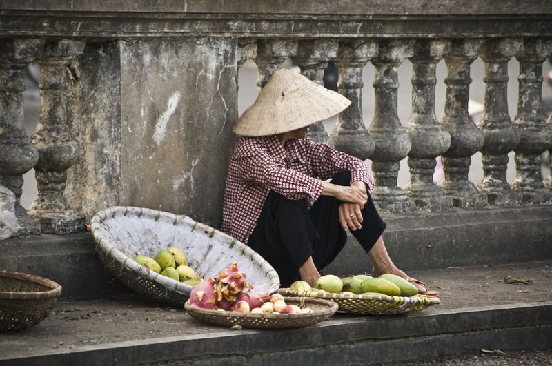 Vendor selling fruits on sidewalk against railing