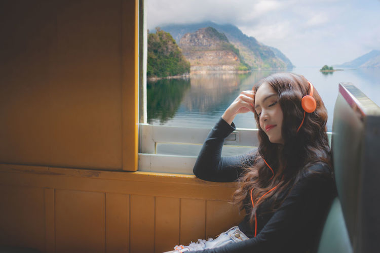 Woman wearing headphone while sitting in train
