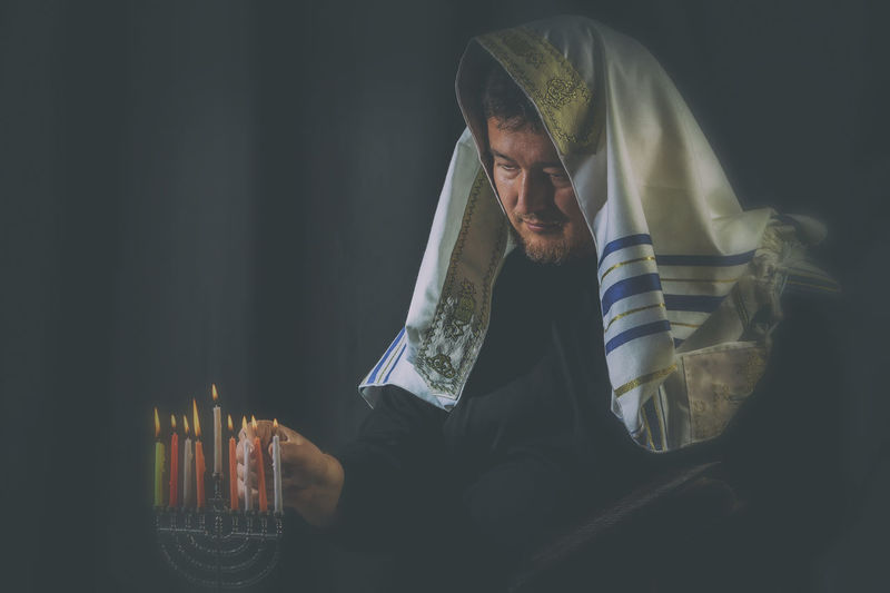 Mature man burning candles in darkroom