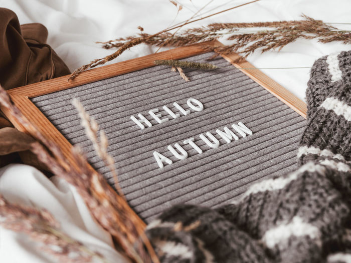 Letter board with season greeting hello autumn. crumpled textile background with warm outfits.