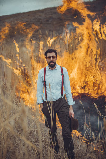 Portrait of man standing against forest fire
