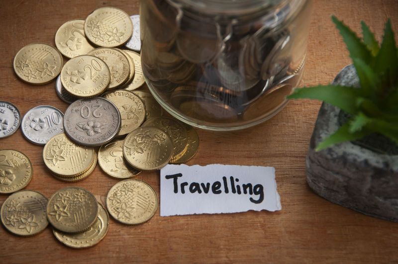 Travelling text on torn paper with coins and wooden table background. holiday concept