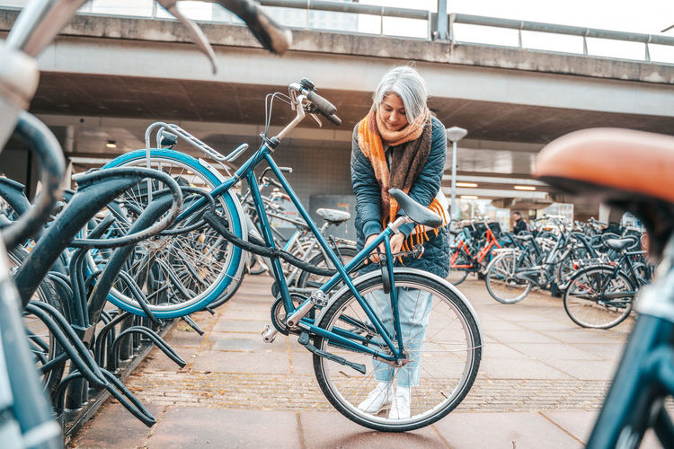 Woman with bicycle standing at bicycle parking station