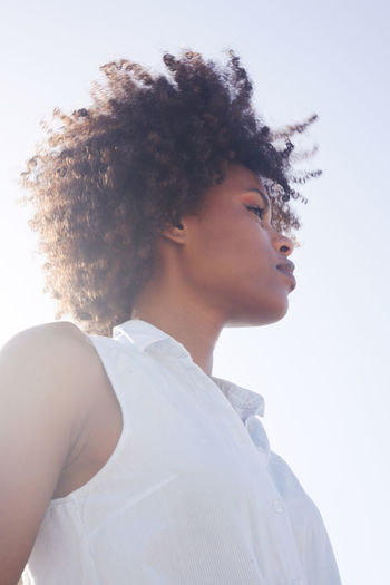 Low angle muted colors portrait of a young black woman with afro hair