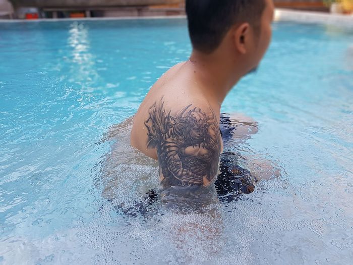 Side view of shirtless man swimming in pool