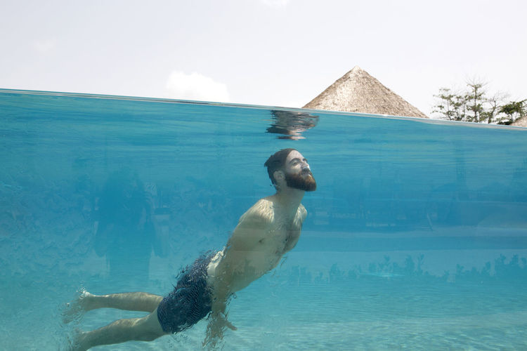 Man swims in glass pool on vacation