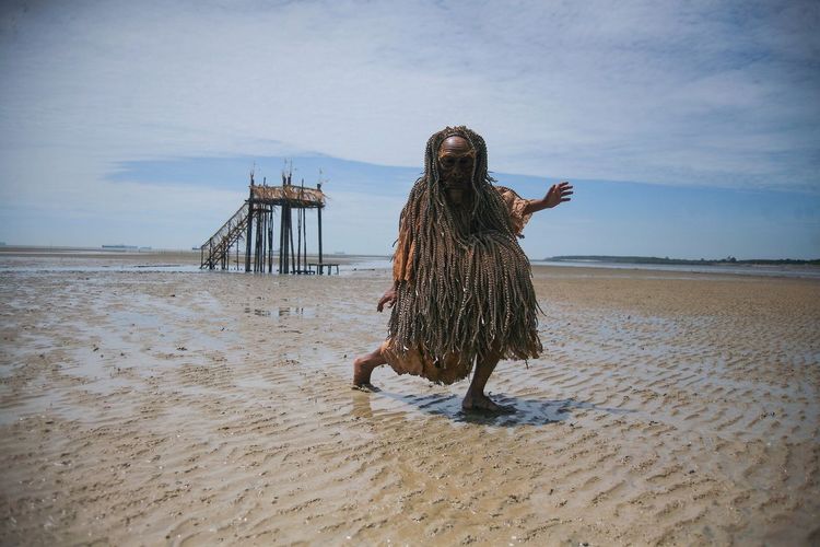 Full length of mah meri tribe man in traditional costume at sandy beach