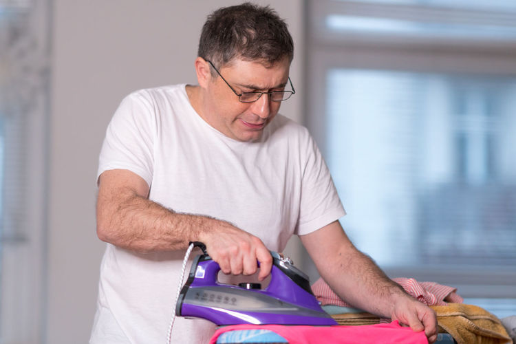 Man ironing cloth at home