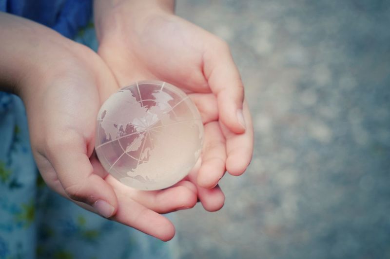 Close-up of hands holding globe outdoors