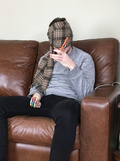 Man with textile over face with sitting on sofa at home