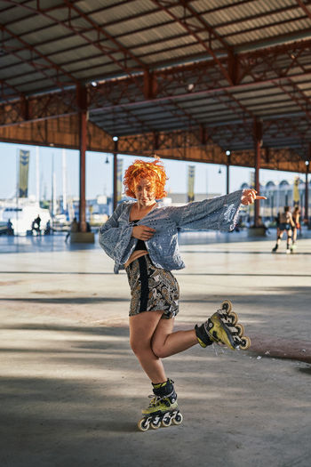 Young alternative redhead dancing in roller skates inside a hangar
