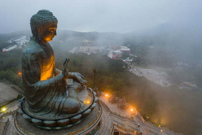 Statue against illuminated building and mountains