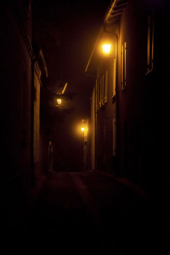 Illuminated street amidst buildings at night