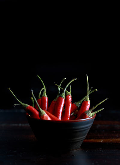 Red hot chili peppers bowl on wooden table and black background..