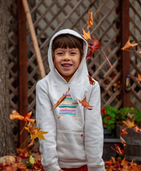 Portrait of cute girl throwing leaves standing outdoors during autumn