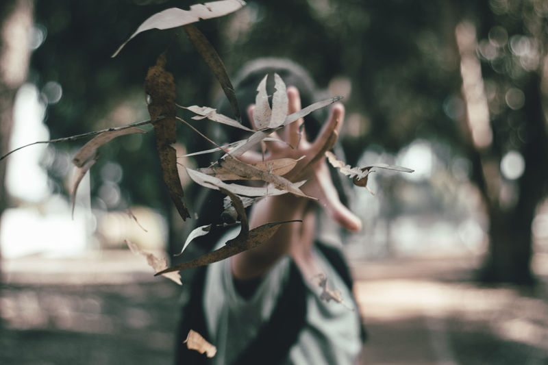 Woman throwing dry leaves in park