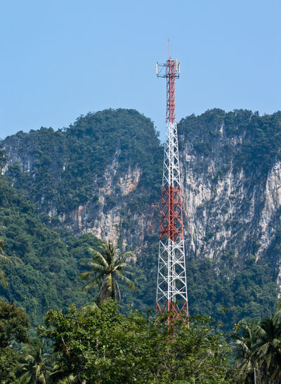 Communications tower and trees against sky