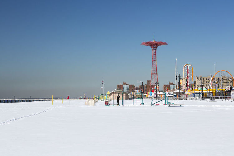 Parachute jump at coney island against clear sky in city during winter