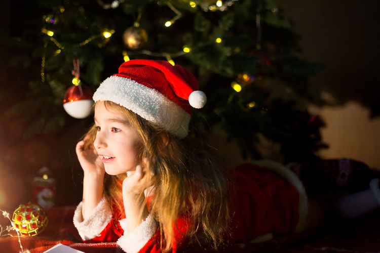 Cute girl lying down by illuminated christmas tree