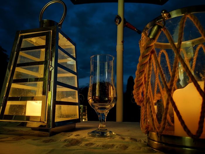 Close-up of wine glass on table at dusk, with candle light