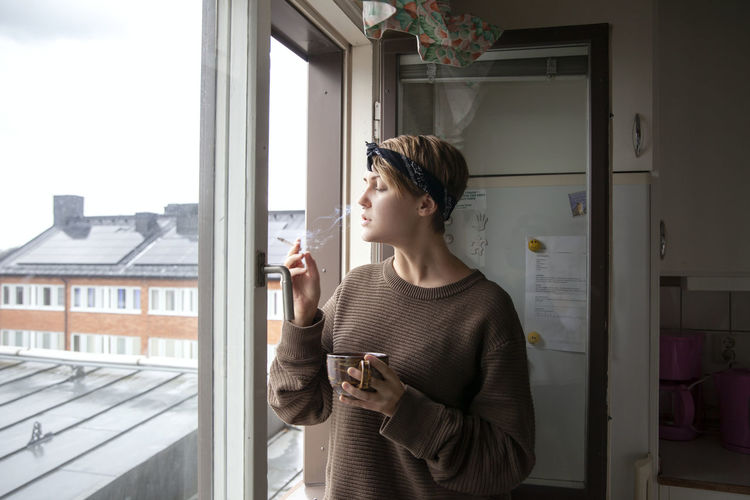 Woman smoking cigarette at window