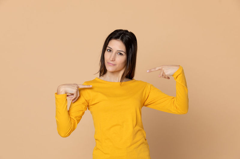Portrait of smiling woman standing against yellow background