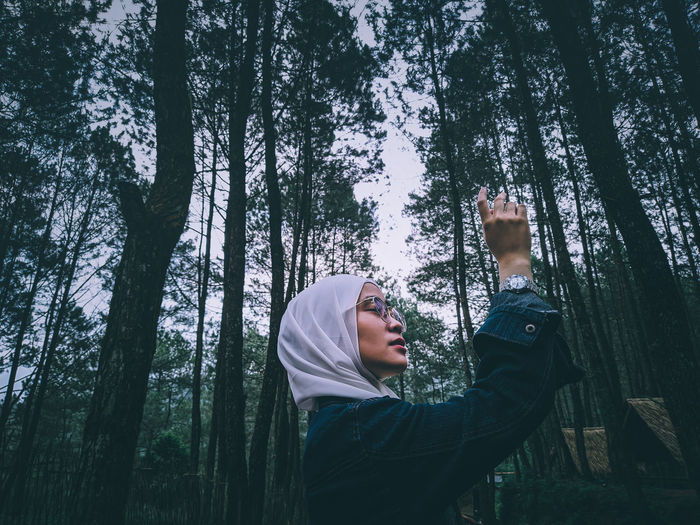 Woman standing by trees in forest