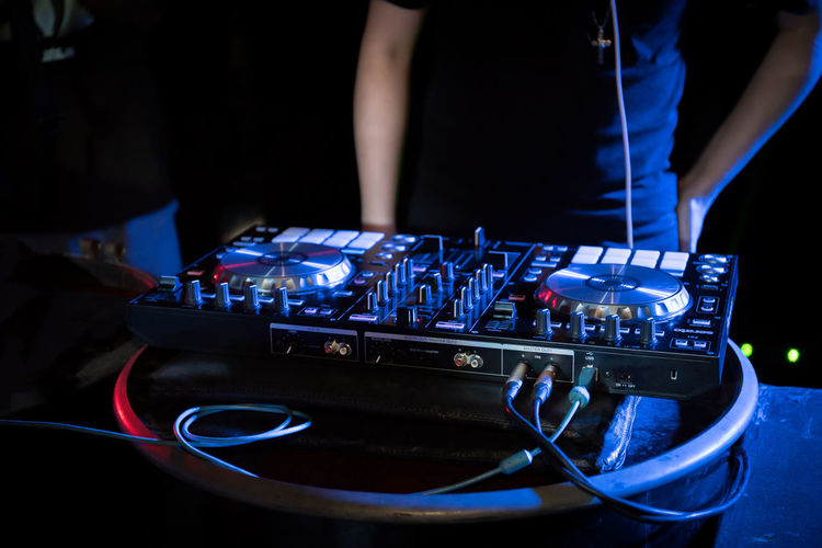 Midsection of man operating sound mixer at nightclub