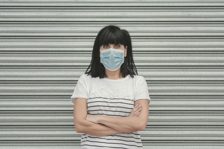 Portrait of a young woman standing against closed shutter
