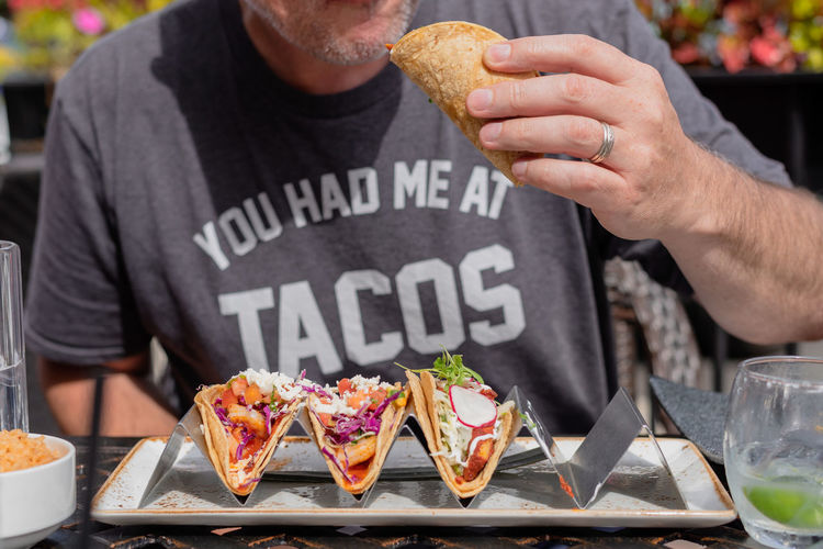 Midsection of man eating tacos