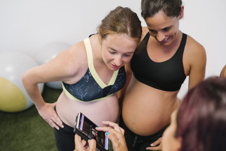 Pregnant watching exercises on smart phone