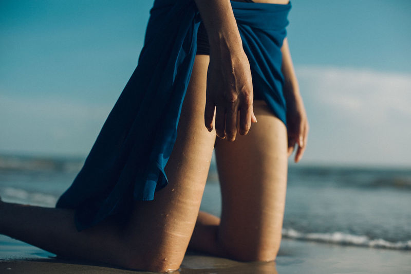 Low section of woman kneeling on beach
