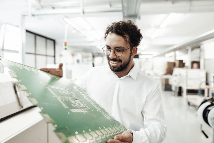 Smiling male technician analyzing large computer chip in industry