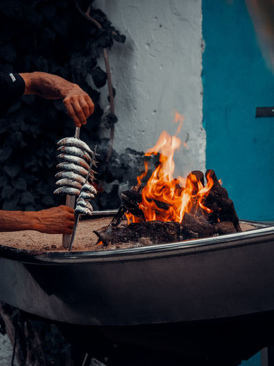 Man cooking sardines on fire