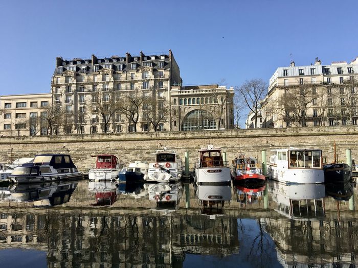 Reflection of buildings and boats on seine river in paris city against clear sky