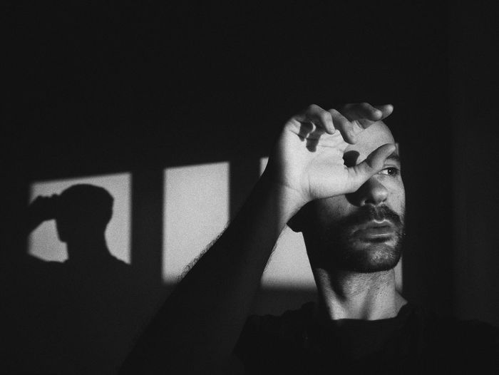 Man looking away while sitting in darkroom