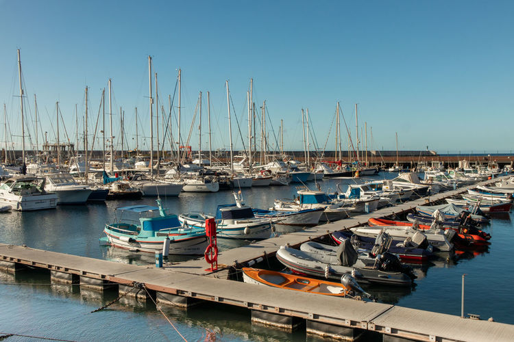 Sailboats moored at harbor against clear blue sky