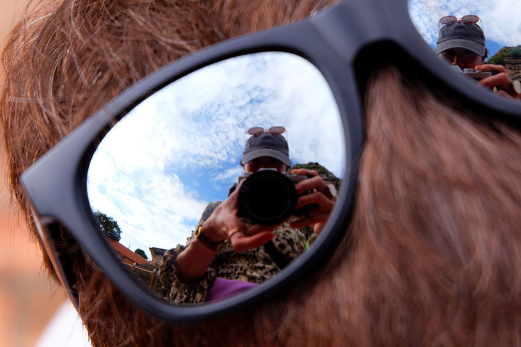 Reflection of person photographing in sunglasses