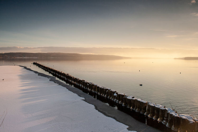 Pier over sea against sky during sunset