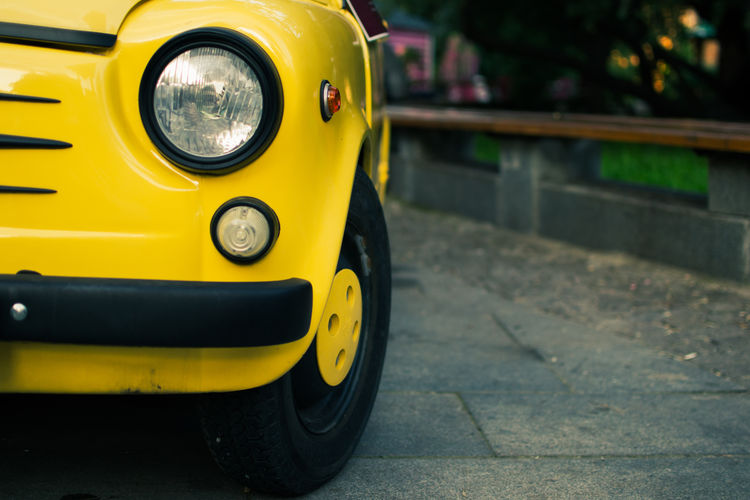 Close-up of yellow car on street