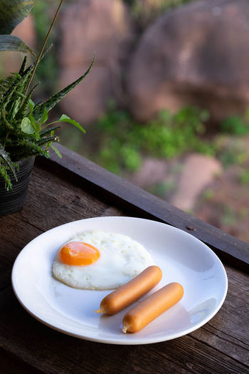 American breakfast with eggs and sausage put on white plate, wood background. food concept.