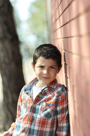 Portrait of boy standing by brick wall