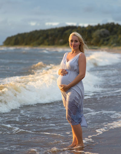Portrait of pregnant woman standing on beach