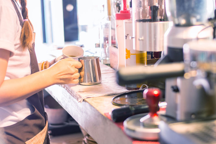 Midsection of woman preparing coffee in kitchen