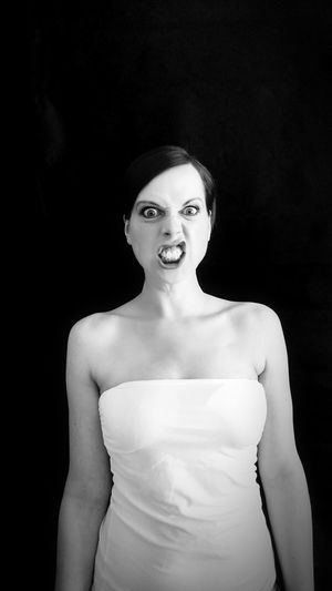 Portrait of angry woman standing against black background