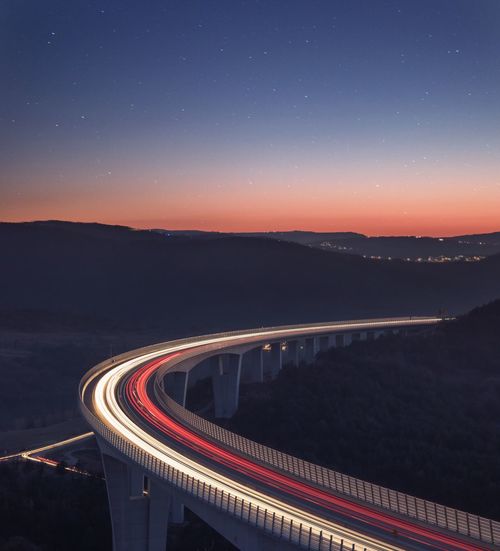 High angle view of light trails on bridge against sky at night