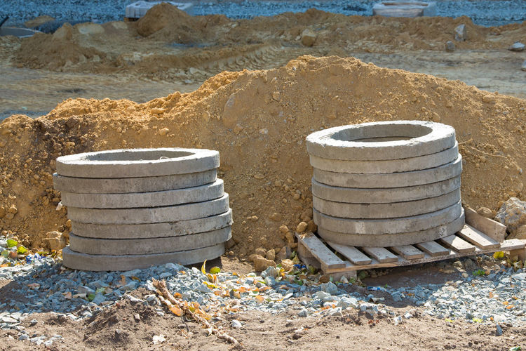 Reinforced concrete rings lie on pallets construction site.