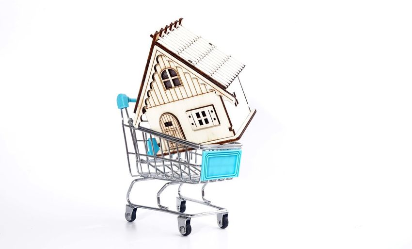A wooden house in a shopping cart / online house sale concept